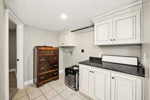Kitchen with baseboards, dark stone countertops, and light tile patterned flooring