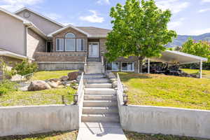 View of front of home with a front yard, brick siding, a carport, and a mountain view