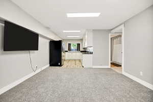 Unfurnished living room featuring light carpet and baseboards