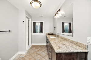 Bathroom with a chandelier, vanity, baseboards, and a textured ceiling