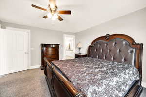 Bedroom with light carpet, baseboards, a ceiling fan, and ensuite bathroom
