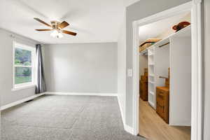 Unfurnished bedroom featuring baseboards, light carpet, a textured ceiling, ceiling fan, and a spacious closet