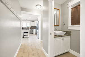 Corridor featuring a sink, light wood finished floors, and baseboards