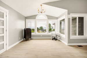 Sitting room featuring a chandelier, light wood-style flooring, vaulted ceiling, a desk, and baseboards