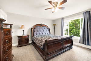 Bedroom with light colored carpet, baseboards, and a ceiling fan