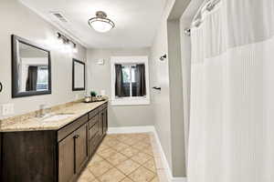 Full bathroom featuring tile patterned floors, vanity, a textured ceiling, and baseboards