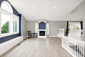 Unfurnished living room with wood finished floors, a glass covered fireplace, baseboards, and recessed lighting