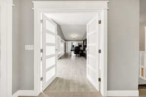 Hallway with a desk, light wood-type flooring, and lofted ceiling