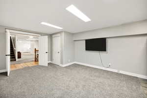 Finished basement featuring carpet, baseboards, stairs, and tile patterned flooring