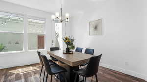Dining room with baseboards, a chandelier, and dark wood-style floors