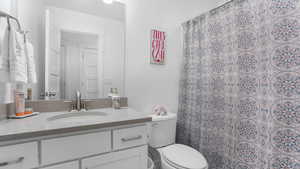 Full bathroom with vanity, toilet, and a shower with shower curtain