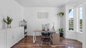 Office space featuring baseboards and dark wood-type flooring