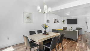 Dining space featuring wood finished floors, a chandelier, and baseboards
