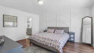 Bedroom featuring wood finished floors, baseboards, and ensuite bathroom