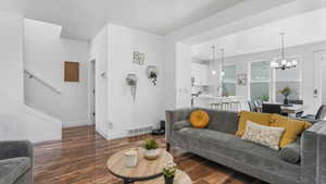 Living room with wood-type flooring, a chandelier, baseboards, recessed lighting, and stairway