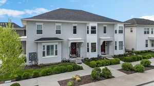 View of front facade featuring stucco siding and roof with shingles