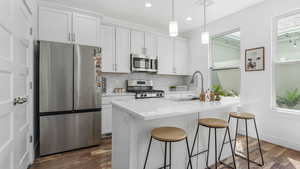 Kitchen with stainless steel appliances, a sink, decorative backsplash, recessed lighting, and white cabinetry