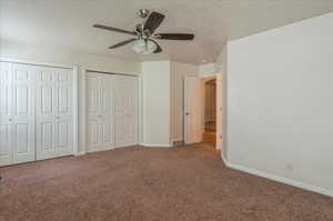 Unfurnished bedroom with carpet flooring, multiple closets, baseboards, a ceiling fan, and a textured ceiling