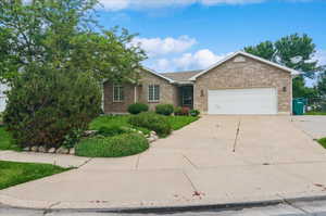 Single story home with brick siding, driveway, and an attached garage