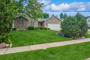 Ranch-style home with brick siding, a garage, and a front yard