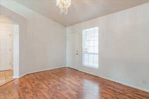 Empty room with arched walkways, wood finished floors, baseboards, and a chandelier