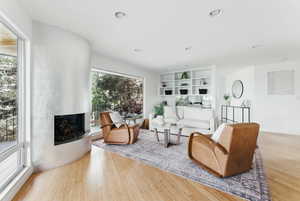 Living room with a fireplace, wood finished floors, and recessed lighting