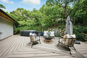 Wooden deck featuring a hot tub, an outdoor hangout area, and view of scattered trees