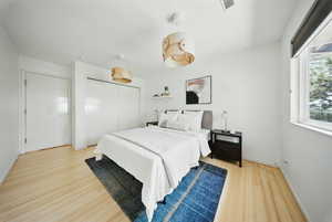 Bedroom with wood finished floors, a closet, and baseboards