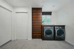 Washroom featuring washing machine and clothes dryer, carpet flooring, and baseboards