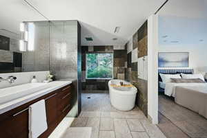 Ensuite bathroom with tile walls, a freestanding tub, vanity, and walk in shower