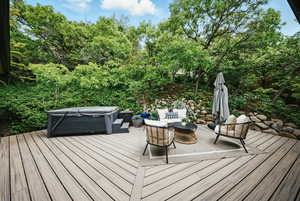 Wooden terrace featuring a hot tub and view of scattered trees