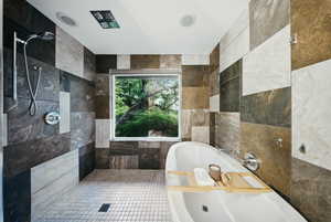 Bathroom with a soaking tub, tile walls, and tiled shower