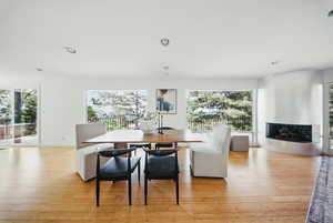 Dining area with plenty of natural light, a fireplace, light wood-style floors, recessed lighting, and baseboards