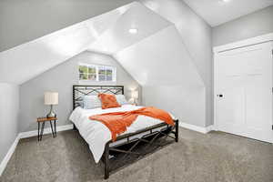 Bedroom with carpet, baseboards, lofted ceiling, and a textured ceiling
