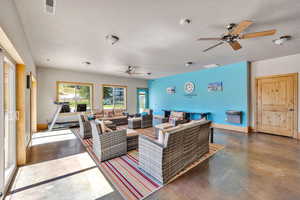 Living area featuring ceiling fan, finished concrete floors, a textured ceiling, and baseboards