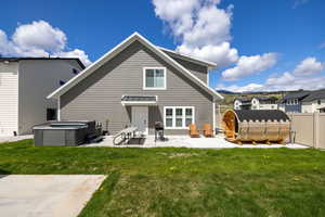 Rear view of property featuring a hot tub and a patio