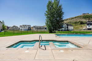 Community pool with a hot tub, a residential view, a patio area, and a mountain view