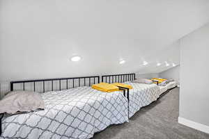 Carpeted bedroom featuring baseboards and lofted ceiling