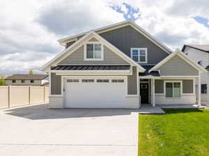 View of front of house featuring driveway, board and batten siding, an attached garage, and a standing seam roof