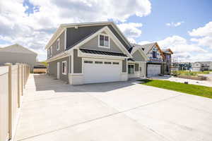 View of front of house featuring a garage, a standing seam roof, concrete driveway, metal roof, and board and batten siding