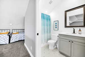 Full bathroom with vanity, toilet, lofted ceiling, and connected bathroom