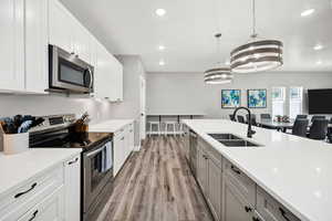 Kitchen featuring appliances with stainless steel finishes, a sink, recessed lighting, light countertops, and light wood finished floors