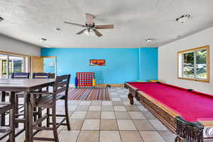 Playroom with ceiling fan, light tile patterned floors, billiards, and a textured ceiling