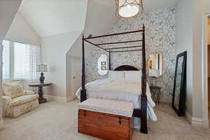 Carpeted bedroom featuring wallpapered walls, vaulted ceiling, and baseboards