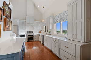 Kitchen with appliances with stainless steel finishes, backsplash, light countertops, high vaulted ceiling, and hardwood / wood-style floors