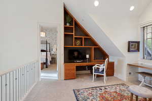 Office area with light carpet, lofted ceiling, and built in shelves