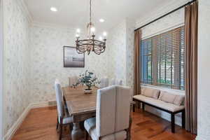 Dining space with a chandelier, hardwood / wood-style flooring, recessed lighting, and ornamental molding
