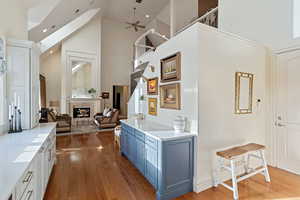 Corridor with high vaulted ceiling, wood-type flooring, and recessed lighting