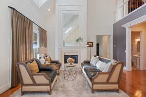 Living room with a towering ceiling, wood finished floors, a fireplace, baseboards, and a skylight