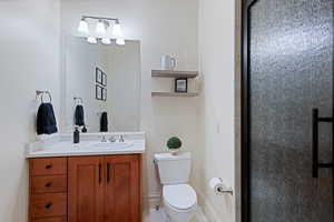 Bathroom with toilet, vanity, and a shower with door